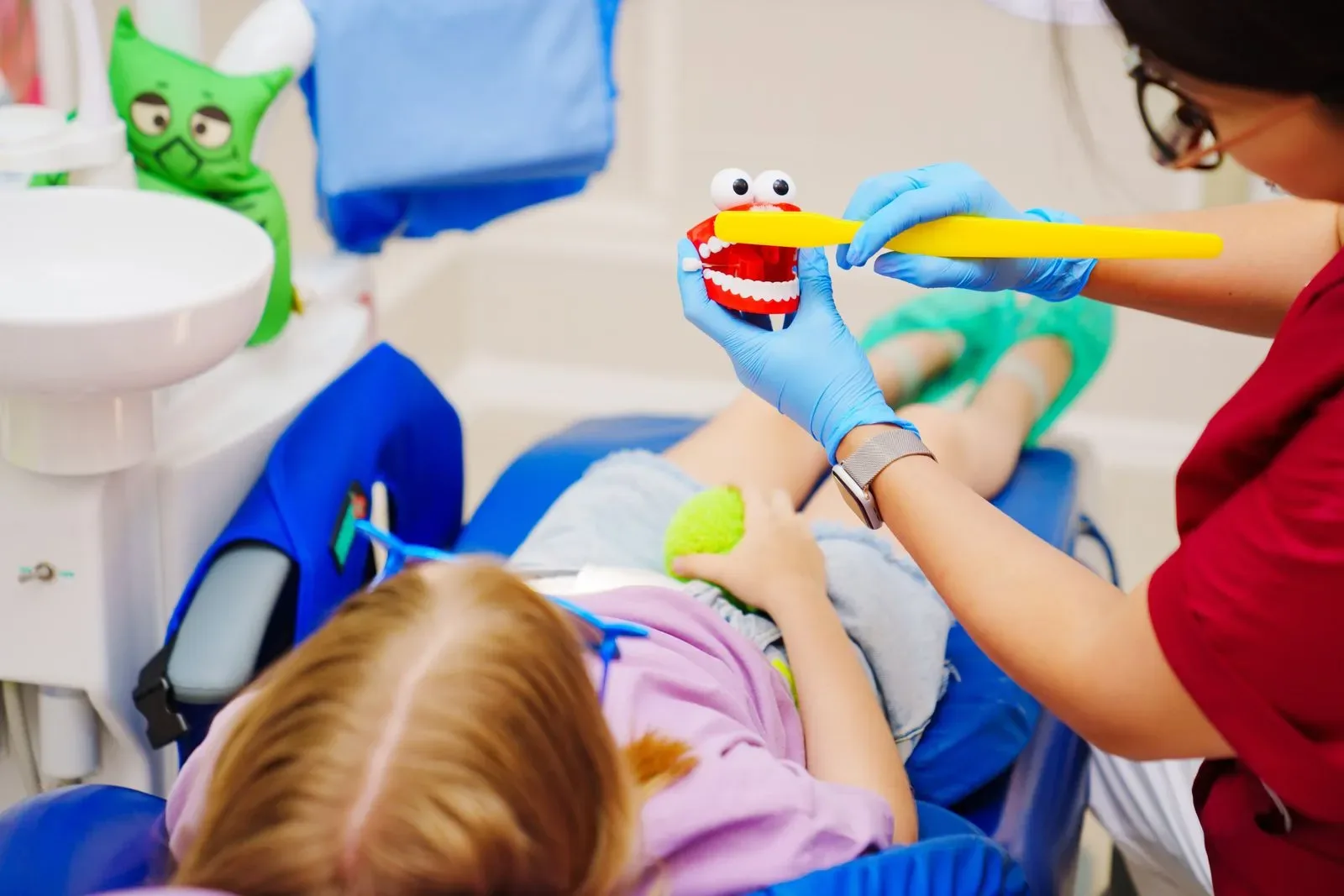 Dental team member using a toy tooth model to calm a young patient