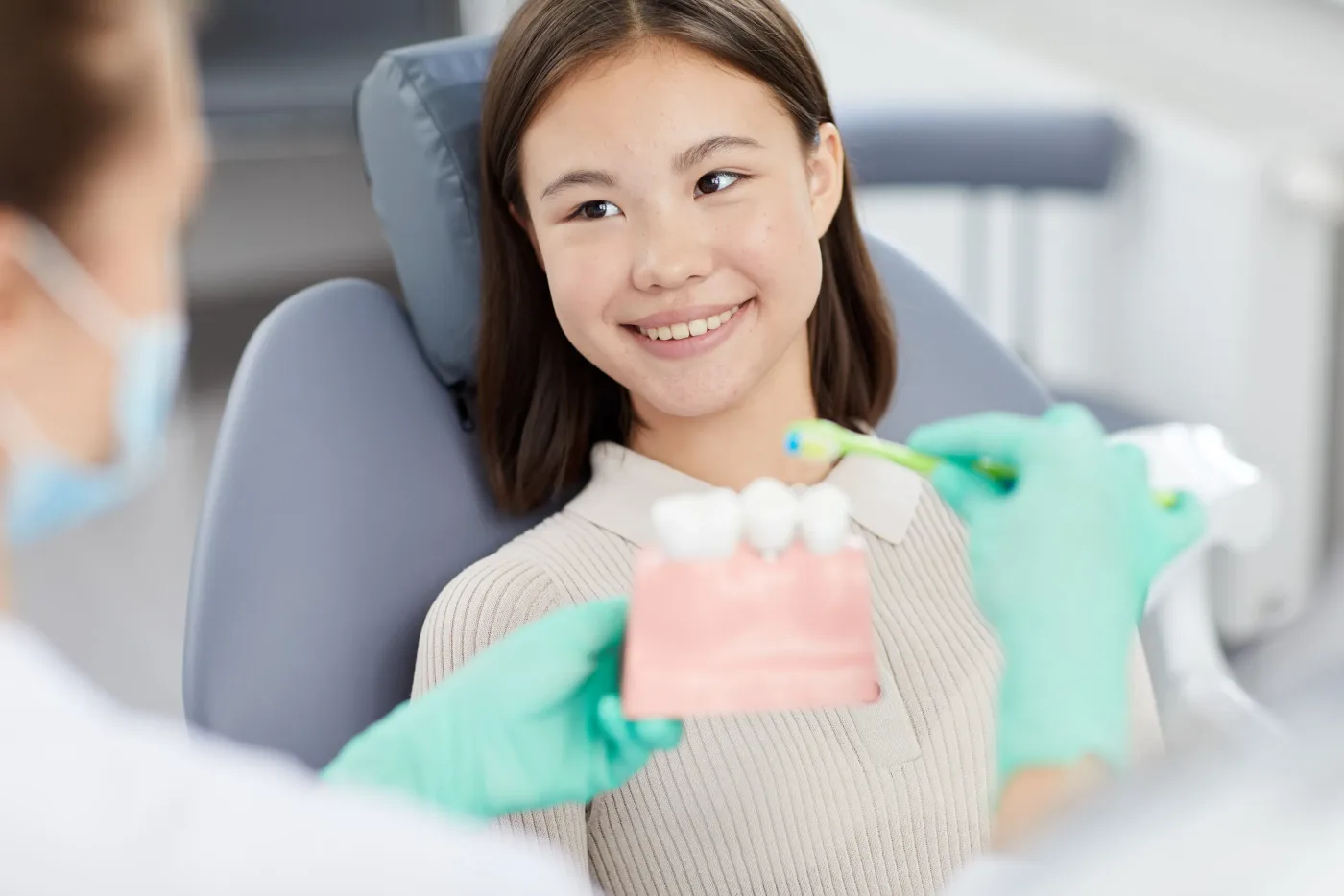 Patient smiling while holding a tooth model during a visit